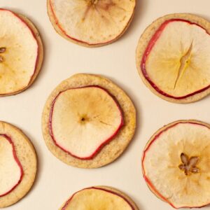 Top-down view of dried apple slices arranged on a beige surface, ideal for food photography.